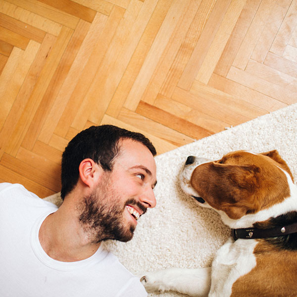 Smiling men and his dog lying on the floor in their living room